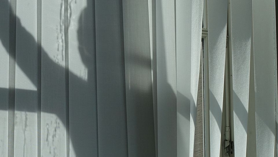 Schattenspiel von einer Person vor einem Fenster 